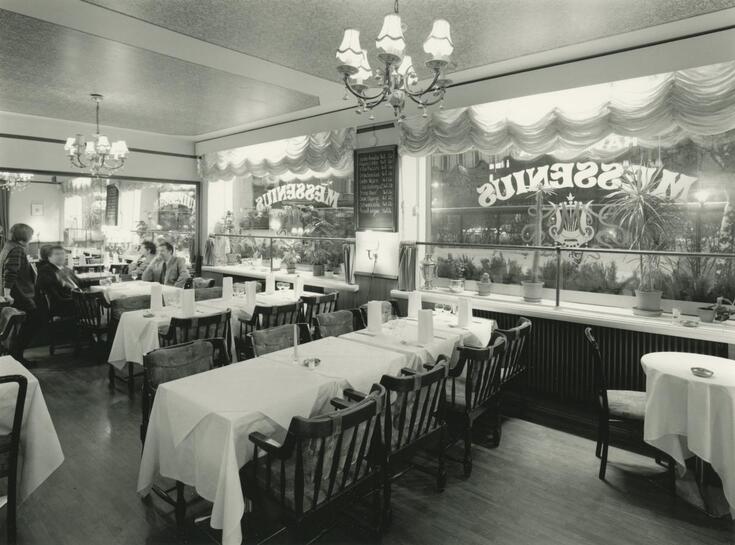 Interiör från salen i restaurang Messenius. Borden är klädda med vita dukar. I bakgrunden syns kunder vid bord.