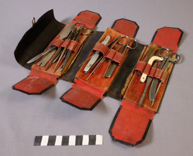 Mustasta nahasta valmistettu (sisus punaista kangasta) välskärin instrumenttikukkaro instrumentteineen. 15 erilaista instrumenttia pujotettuna kukkarossa oleviin lenkkimäisiin pidikkeisiin.