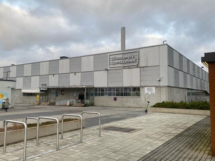 Laatikkomainen harmaa rakennus, jonka seinässä lukee Liikuntamylly, Sportkvarnen.