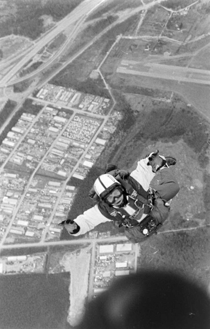 Tuntematon hyppääjä vapaassa pudotuksessa heti uloshypyn jälkeen. Hyppääjän vieressä näkyy Tattarisuon teollisuusalue.