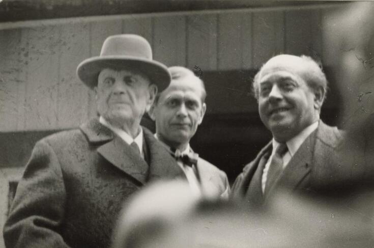 Sibeliuksella on päällystakki ja hattu, muilla miehillä on puku. 