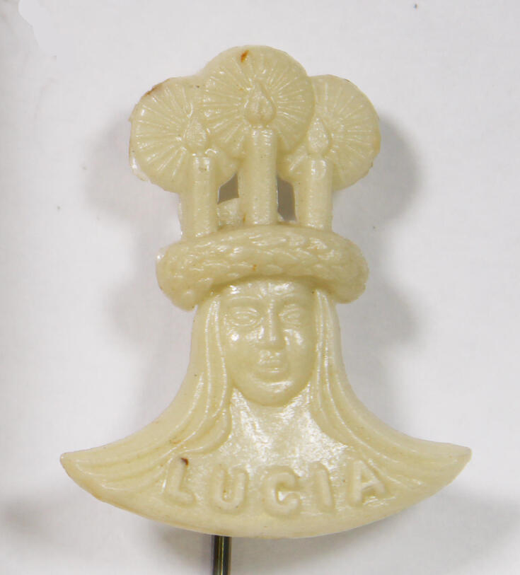 Ett vitt märke i form av Lucias huvud med texten LUCIA nertill. 