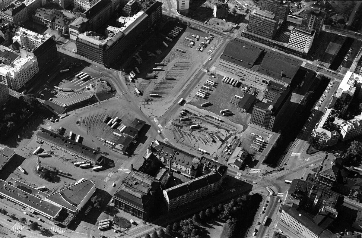 Snedflygfoto från ett litet flygplan (Cessna 172, beteckning ÊOH-CBS) från Posthuset mot söder. I förgrunden till vänster syns Glaspalatset, busstationsbyggnaden och Shells bensinstation, i mitten Hankkijahuset och Jordbrukarnas mjölkcentrals byggnad samt Essos bensinstation. Till höger Arkadiagatan och Södra och Norra Järnvägsgatan. Högre upp till vänster Simonsgatan och Kampgatan (nuvarande Urho Kekkonens gata). I mitten Simonsfältet och busstationen, det så kallade Kampfältet och Salomonsgatan. I öv