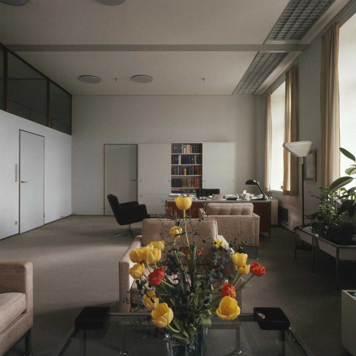 Sisäkuva Helsingin kaupungintalon toimistotiloista. Valoisassa, vaaleassa huoneessa on sohvia ja nojatuoleja. Etualalla kukkakimppu ruukussa.
