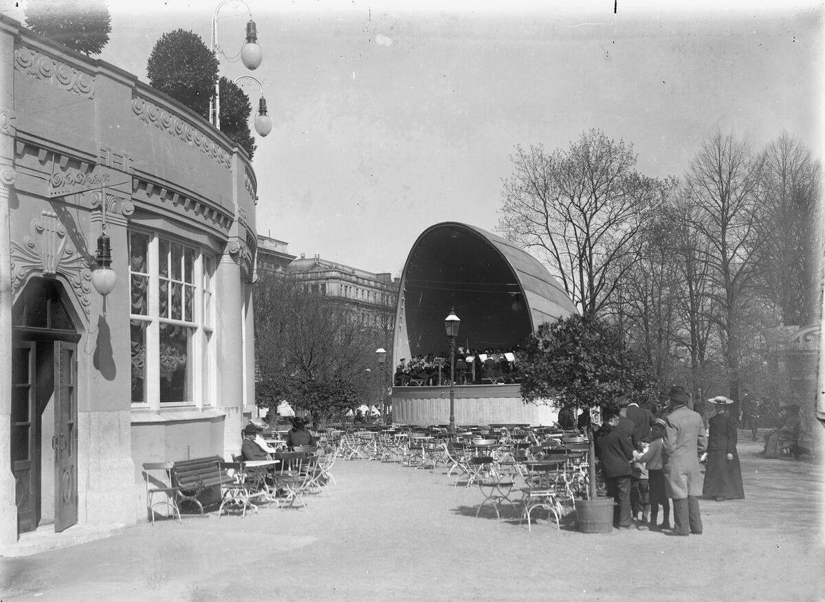 Vasemmalla Ruotsalaisen teatterin kaarevaa julkisivua, jonka vieressä on ulkokahvila ja soittolava. Kahvilassa on asiakkaita ja lavalla on soittajia.