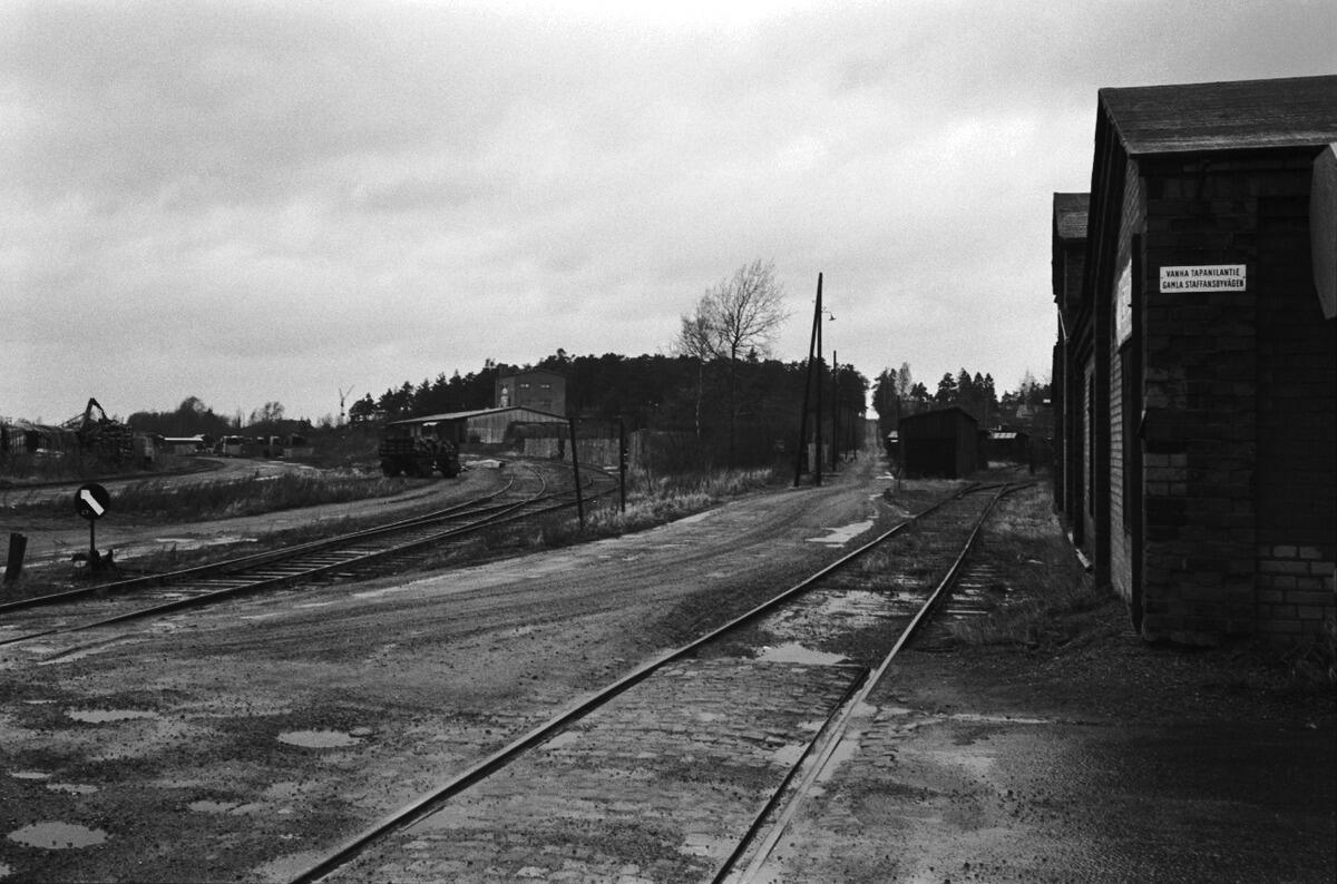 Tapaninkylä, Tapanila. Vanhan Tapanilantien ylittävä teollisuusraide nykyisen Rajatien kohdalla, näkymä pohjoiseen. Taustalla olevalla pienteollisuusalueella sijaitsee nykyisin Hiidenkivenpuisto.