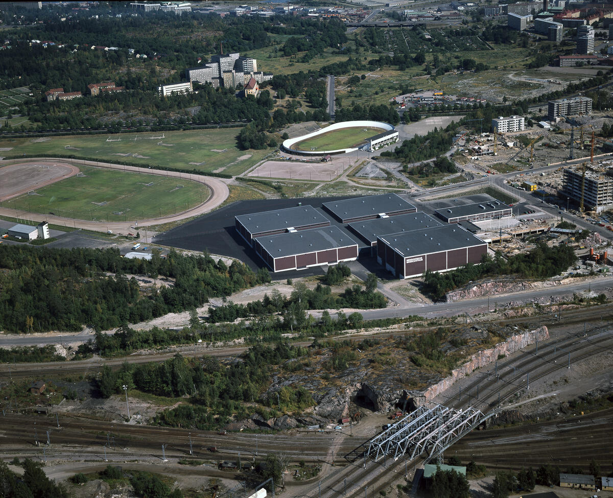 Flygbild från Östra Böle. I mitten av bilden står det splitternya Mässcentret. I förgrunden syns landsvägar , träd och berg, i bakgrunden Velodromen och 