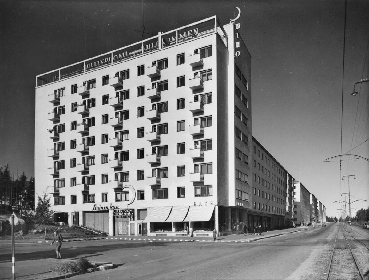 Åbovägen 90 (= Mannerheimvägen 118). Tullbommens byggnad. Arkitekt Olli Pöyry, färdig 1940. En ljus åtta våningars byggnad vars övre del bär neonbokstäverna Tullinpuomi Tullbommen och högra kanten KINO.