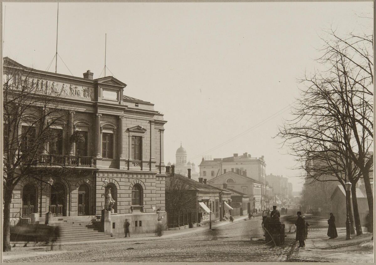 Vy mot Alexandersgatan. Till vänster Alexandersgatan 23, 21 och 19. I bildens vänstra kant Gamla studenthuset, Alexandersgatan 23, arkitekt Hampus Dahlström, fullbordat år 1870.