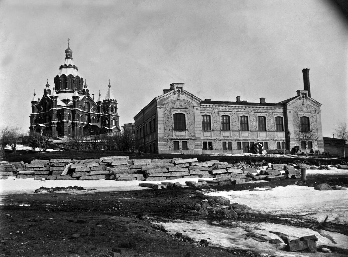 Finska myntverket, en byggnad på två våningar i mitten av bilden. I bakgrunden reser sig Uspenskijkatedralen.  