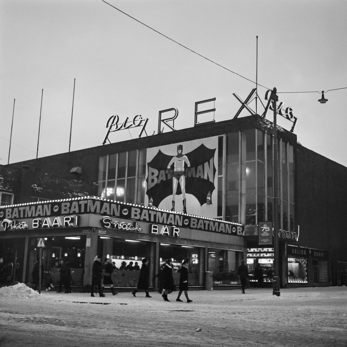 På biografens vägg syns en stor affisch med Läderlappen och texten BATMAN. Texten löper också längs den övre kanten av husets låga del.