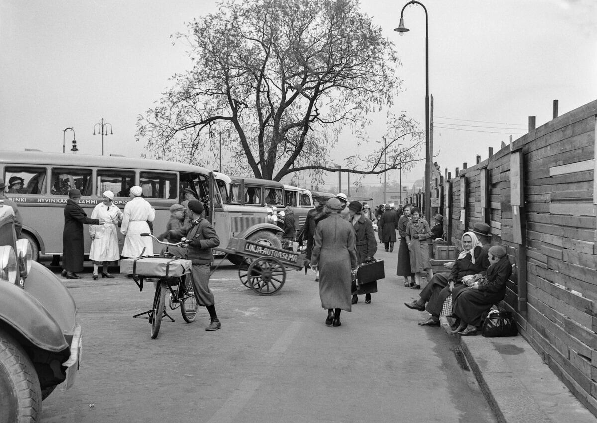 Linja-autoja ja matkustajia Salomonkadulla ja nykyisellä Paasikivenaukiolla. Oikealla olevan lauta-aidan takaa on purettu sisällissodassa 1918 tuhoutuneen Turun kasarmin pohjoissiipi, jonka tilalle valmistui vuonna 1936 Lasipalatsin elokuvateatteri Rex. Kuvassa näkyvä puu on ns. vuonna 1924 suojeltu salava, joka kaatui myrskyssä 29.12.2003. Sen tilalle istutettiin kaatuneen puun pistokkaasta kasvatettu puu.