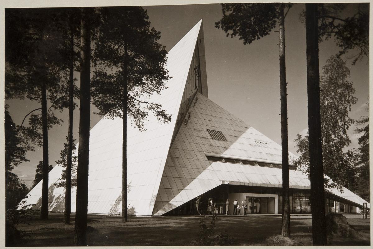 Hyvinkään kirkon julkisivu. Kulmikas, vaalea rakennus näyttää muodostuvan kahdesta toisiinsa sulautuvasta pyramidista.