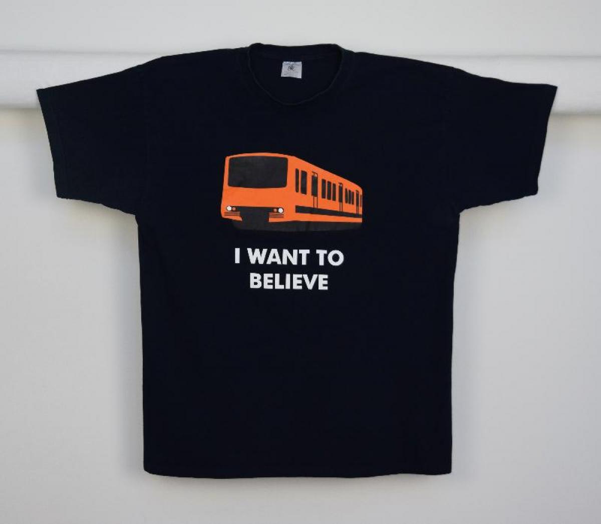 Musta t-paita, jossa metrovaunun kuva sekä teksti "I WANT TO BELIEVE"