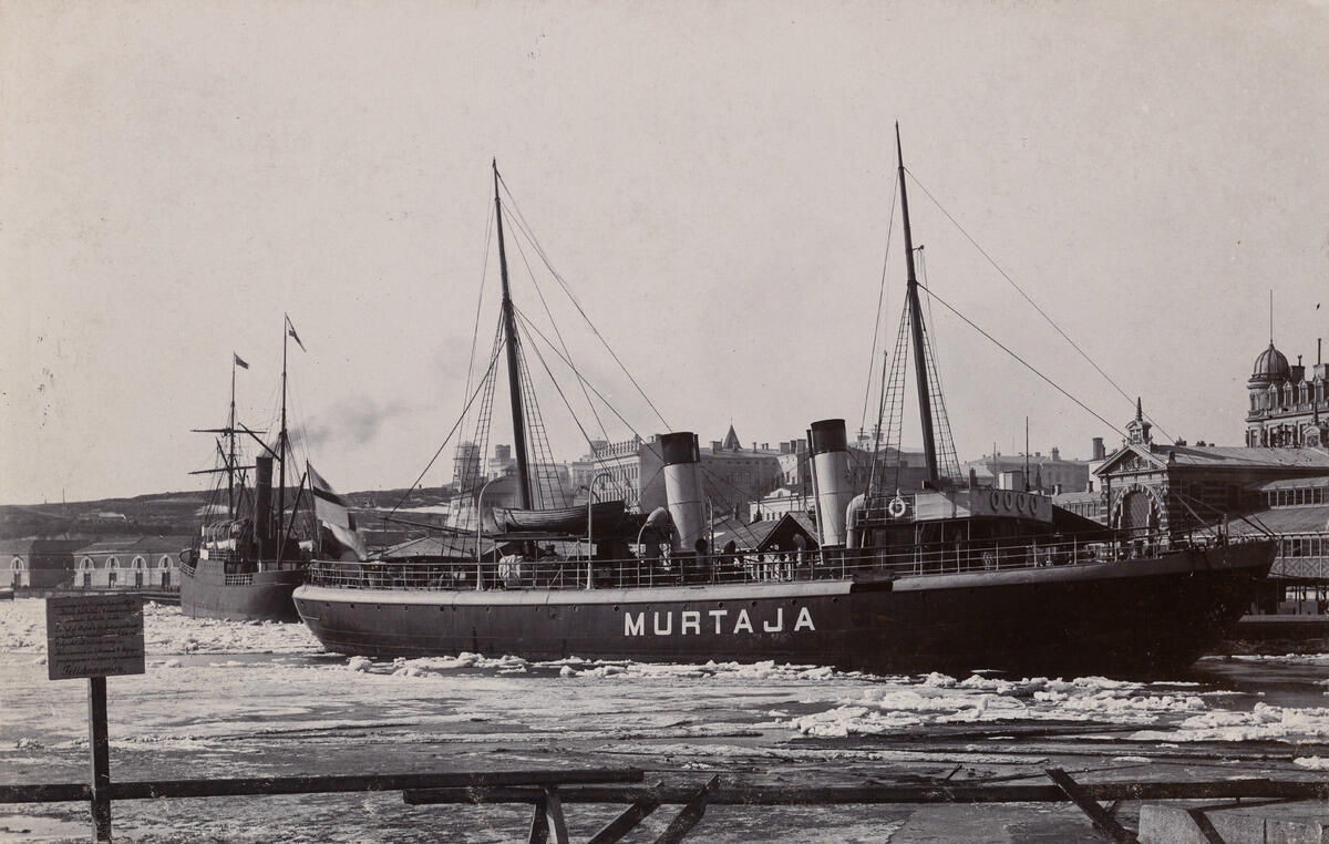 Finlands första isbrytare S/s Murtaja i Södra Hamnen, Norra Kajgrenen (nuvarande Lübeckkajen), framför saluhallen. Fotot togs möjligen i april 1890, då den nybyggda Murtaja anlände till Helsingfors. I vänstra nedre hörnet av bilden finns en skylt där en polis förbjuder att gå på svag is under hot om 4 marks böter.