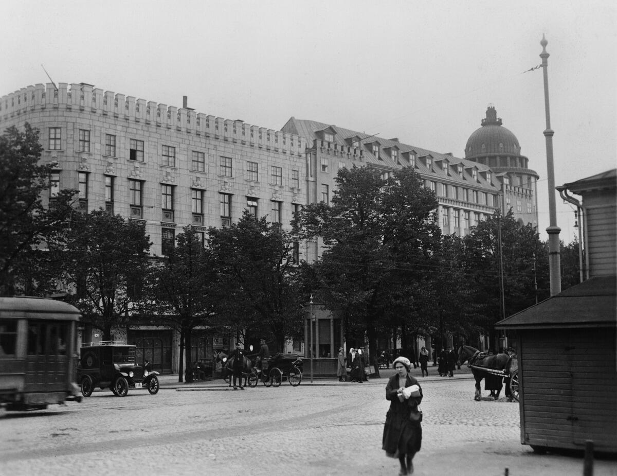 Raitiovaunu, hevosajoneuvoja ja auto Itäisen Heikinkadun (nyk. Mannerheimintie) ja Kaivokadun risteyksessä. Keskellä katua kasvaa puita.