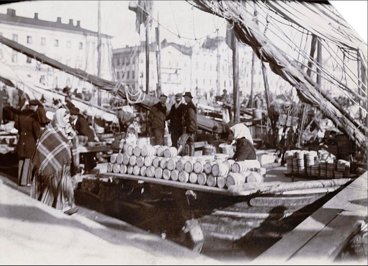 Strömmingsmarknad på gång vid Salutorget intill Kolerabassängen. I bakgrunden syns segelbåtar och folkmängd.