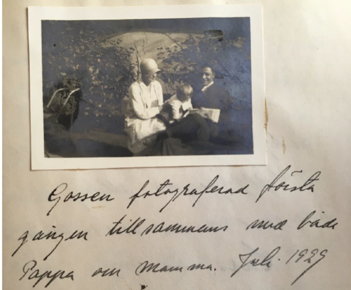 En dagbokssida med ett fotografi och handskriven text. På bilden syns en kvinna med moderiktig klockhatt och en man i kostym. Mellan dem sitter en liten pojke.