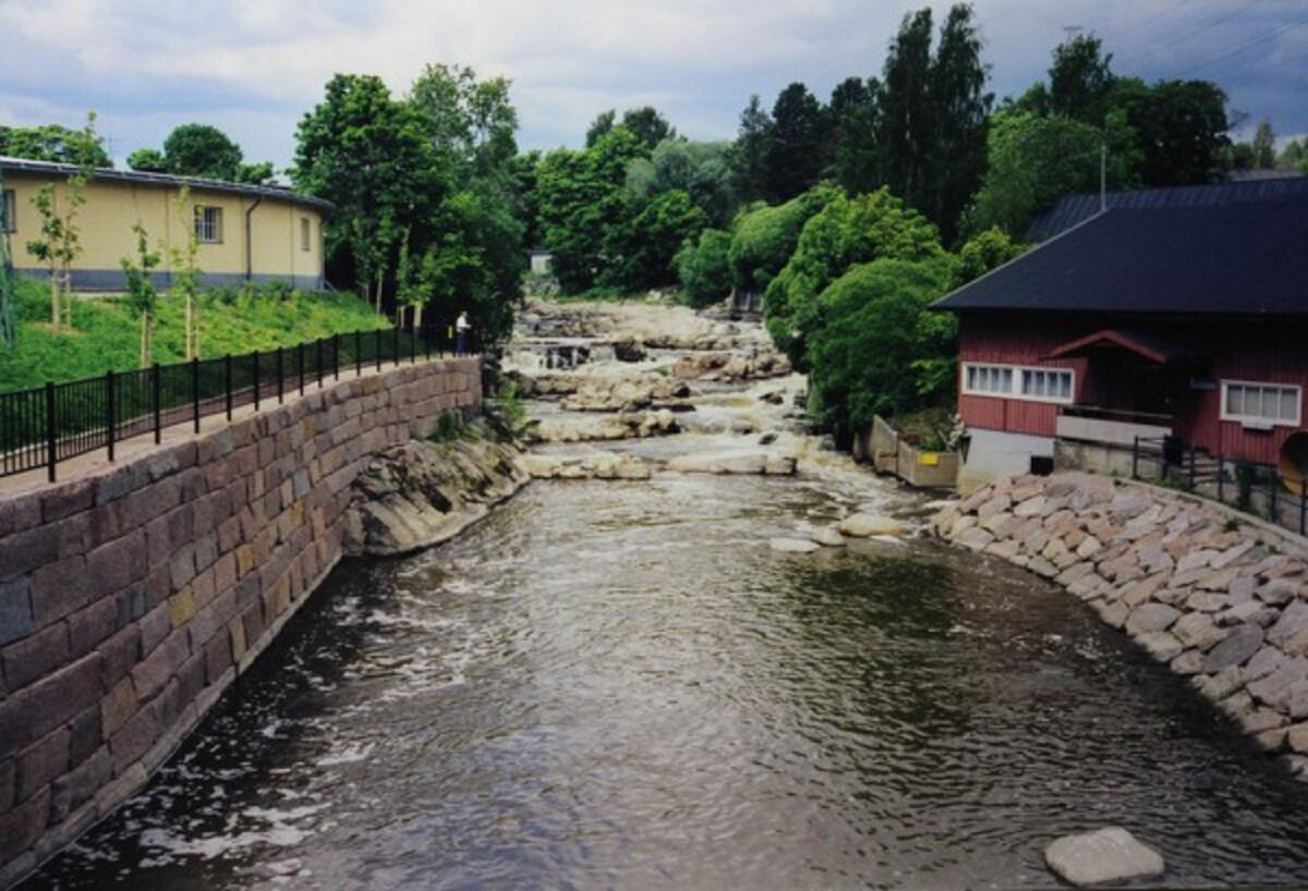 Jokihaaraan rakennetut kalaportaat. Vasemmalla puolella joenuomaa on keltainen puurakennus, oikealla puolella punainen. 