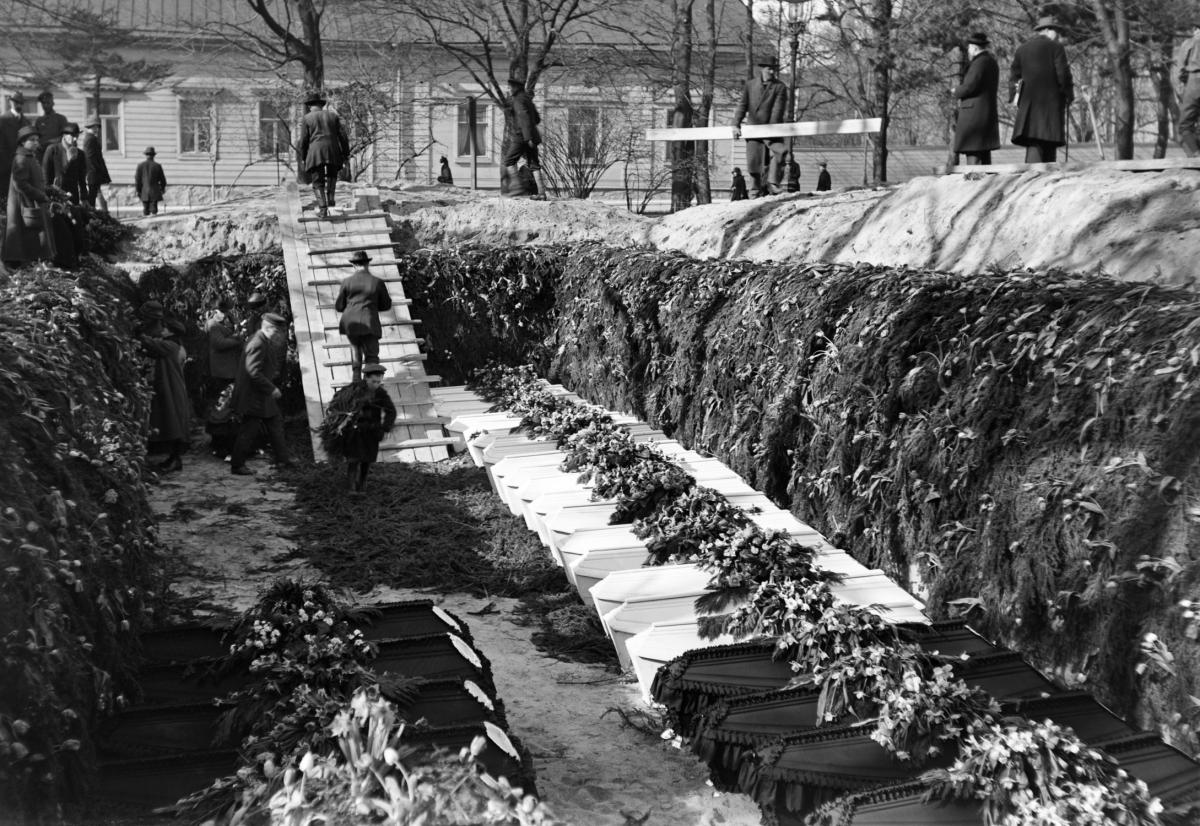 Suuri hauta, jonka pohjalle on laskettu rivi arkkuja.