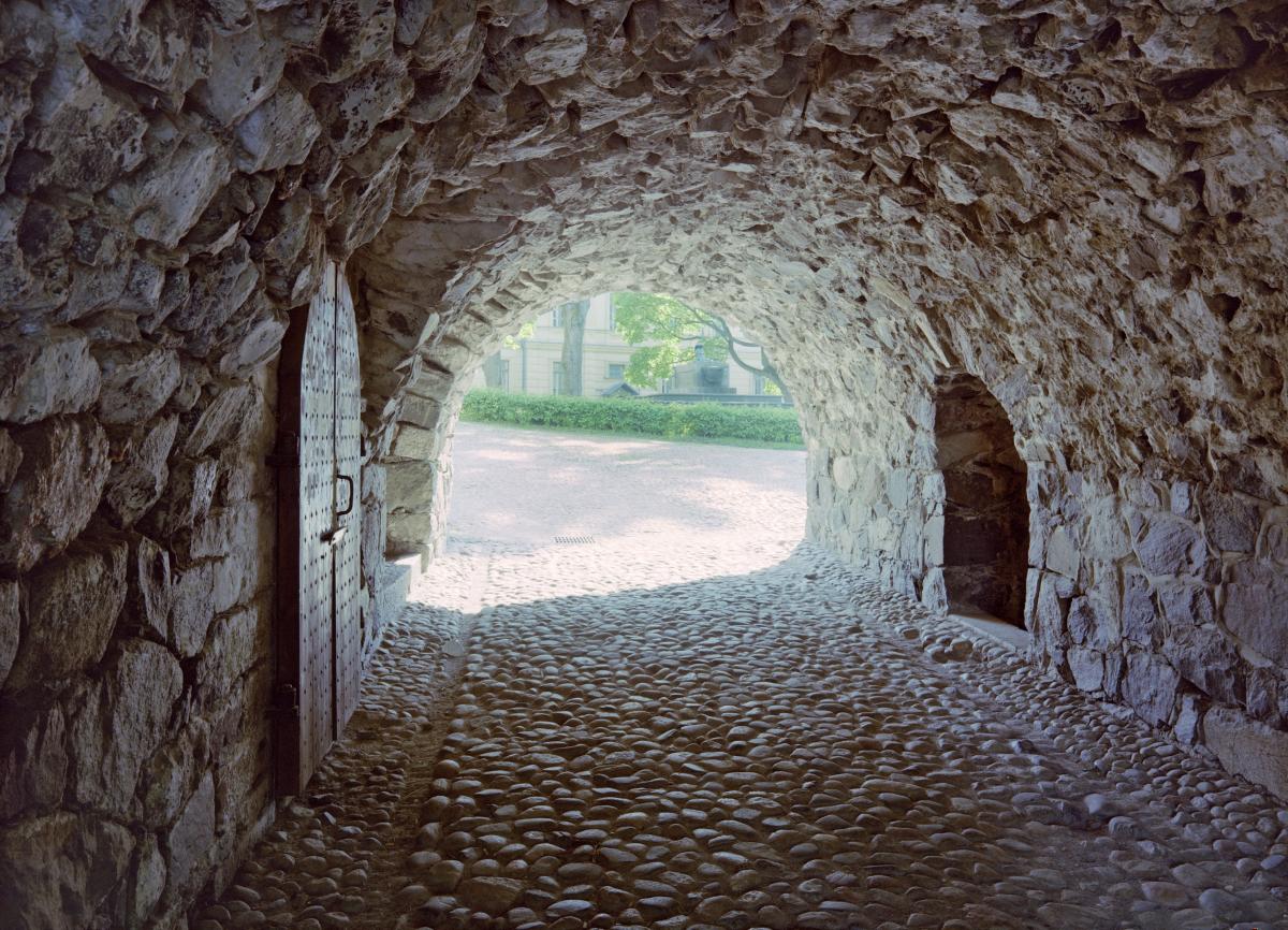 A photo of a stone wall that is several metres thick with a corridor running through it.
