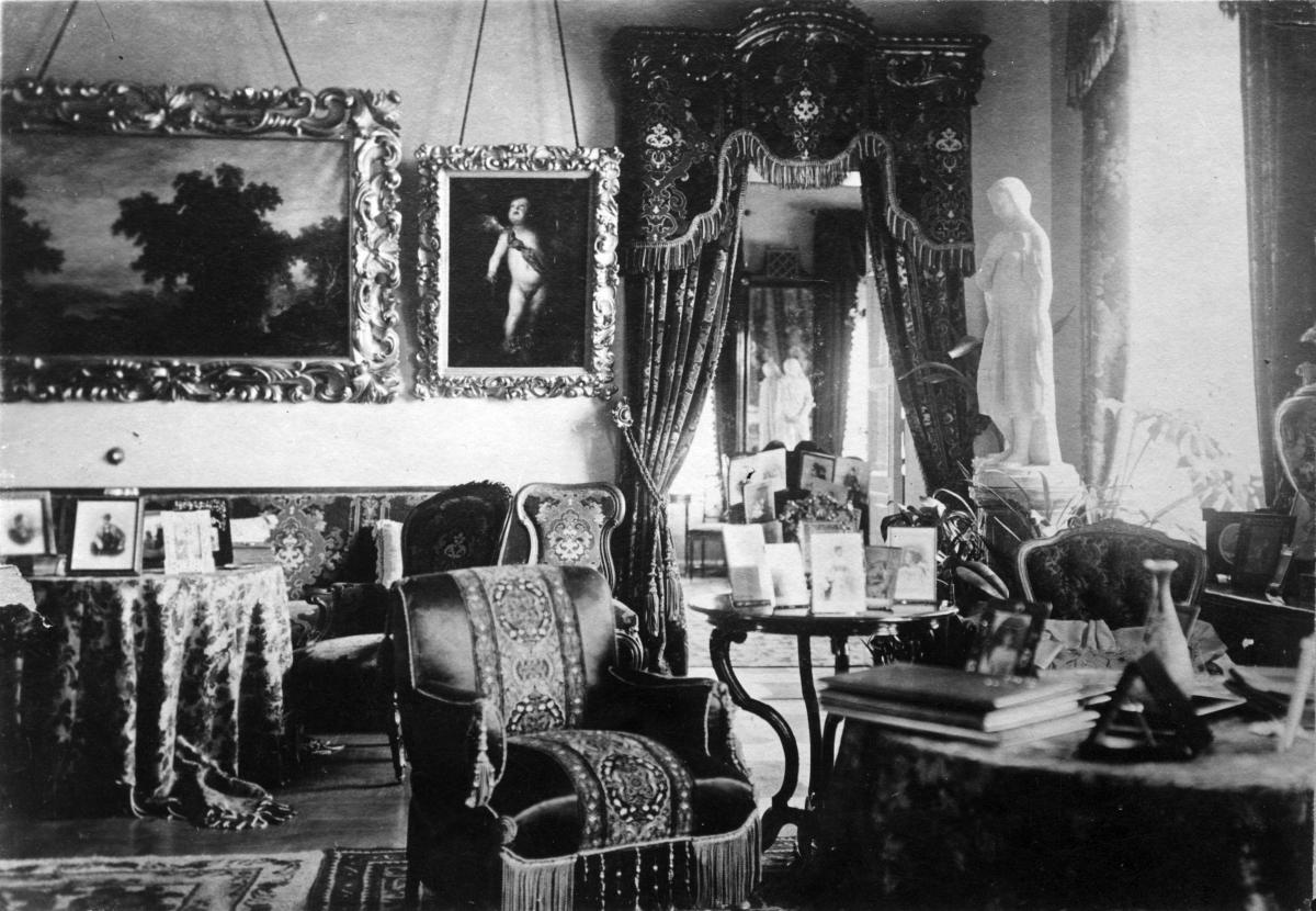 Fotografi av festsalen i Aurora Karamzins hem år 1900. Rummet är fyllt med dekorativa möbler, på borden finns fotografier och på väggarna konst.