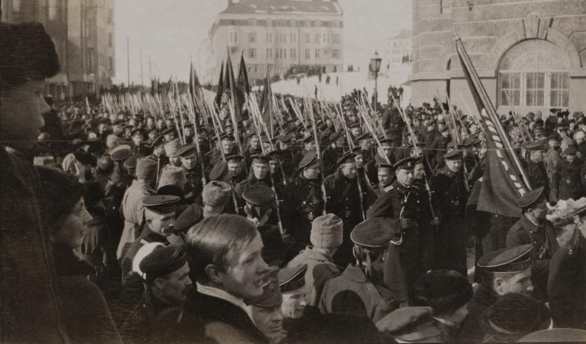 Venäläiset sotilaat juhlivat kulkueessa maaliskuun vallankumousta vuonna 1917. Kulkue on täynnä univormupukuisia miehiä, jotka kantavat lippuja.