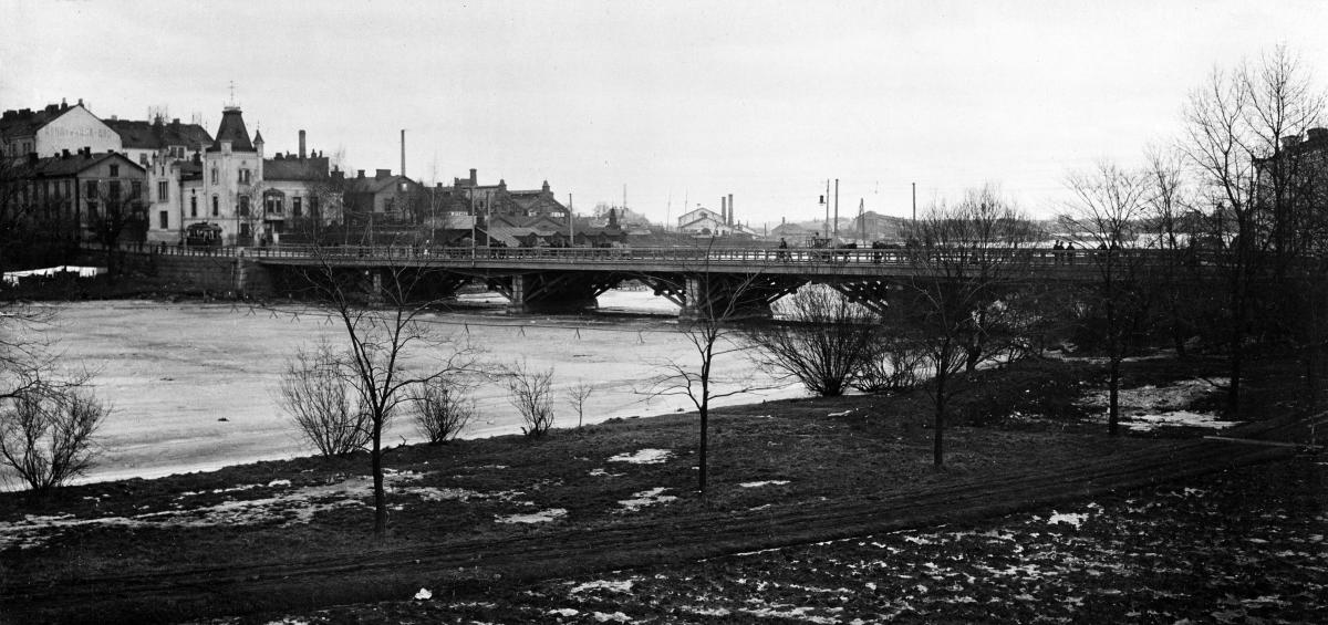Pitkäsilta Kaisaniemen rannasta kuvattuna vuonna 1909. Toisin kuin nykyään, silta on puurakenteinen.