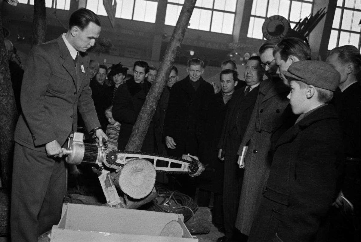 Mies esittelee moottorisahaa yleisölle teollisuusnäyttelyssä vuonna 1945.