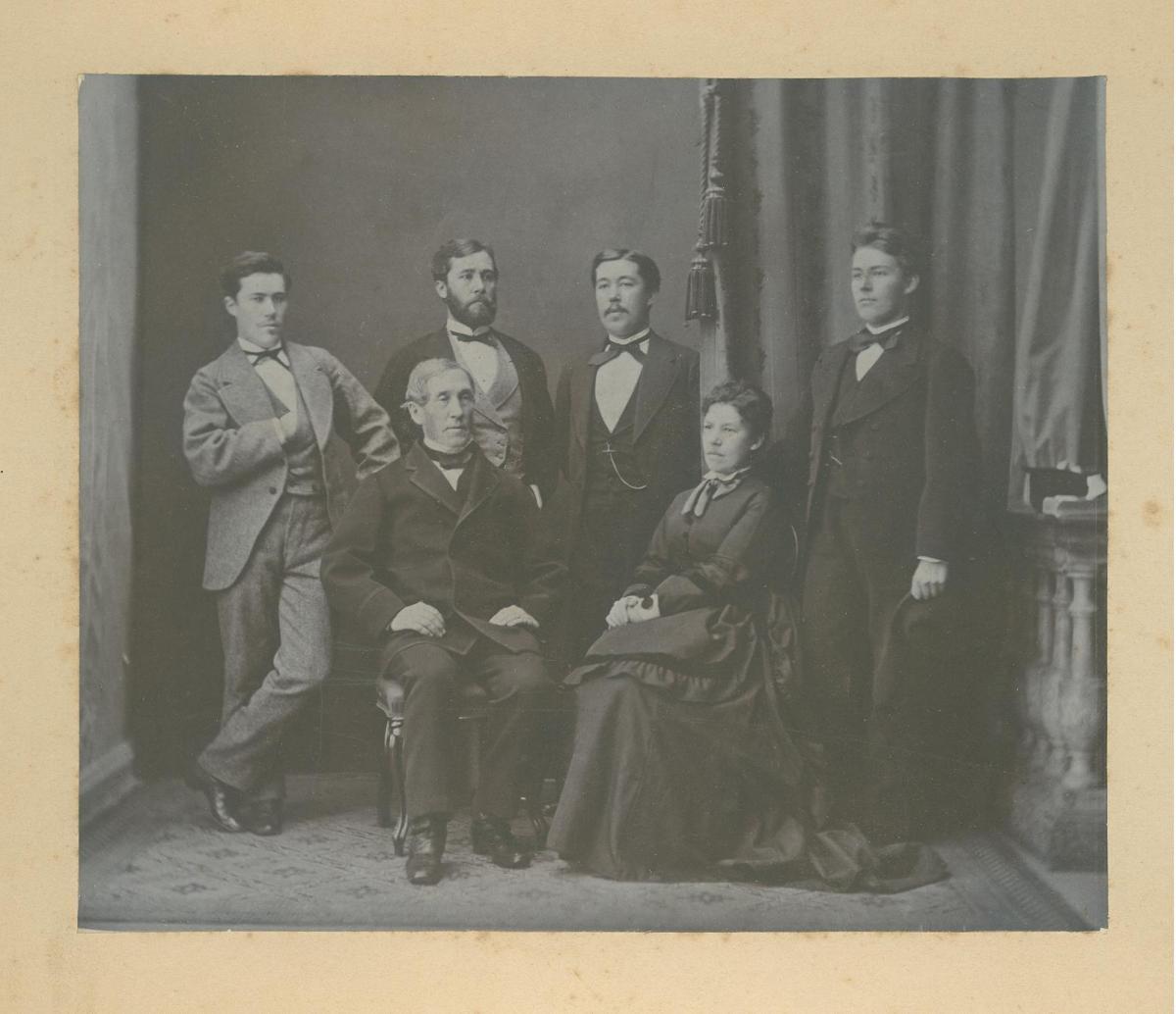 I förgrunden sitter en man och en kvinna på varsin stol, bakom dem står fyra vuxna söner. 