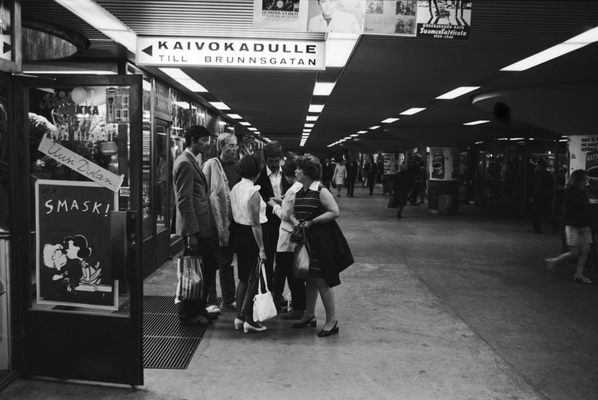 Ihmisiä levykaupan edustalla Asematunnelissa vuonna 1970. Ovessa uuden Bob Dylan -albumin mainos sekä Tenavat-juliste.